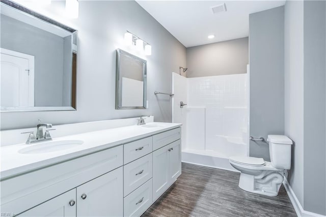 bathroom with a shower, vanity, hardwood / wood-style flooring, and toilet