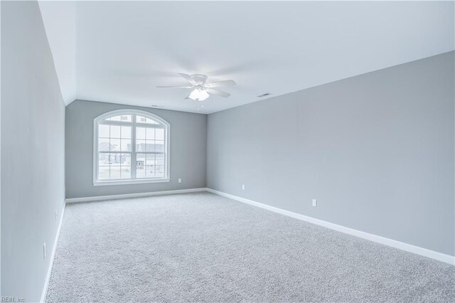 carpeted spare room featuring vaulted ceiling and ceiling fan