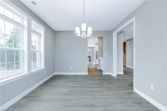 unfurnished dining area featuring hardwood / wood-style floors and an inviting chandelier