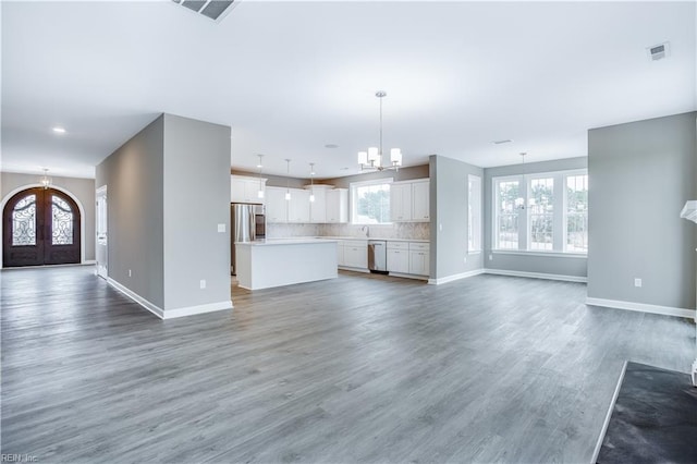 unfurnished living room with french doors, wood-type flooring, and a notable chandelier