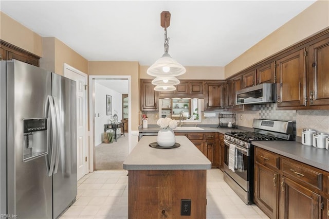 kitchen featuring a center island, sink, tasteful backsplash, decorative light fixtures, and stainless steel appliances