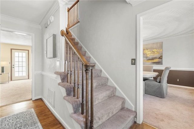 stairway featuring wood-type flooring and ornamental molding