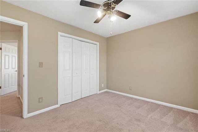 unfurnished bedroom with ceiling fan, light carpet, and a closet