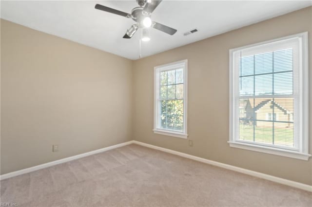 unfurnished room with plenty of natural light, ceiling fan, and light colored carpet