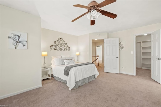 bedroom with a walk in closet, ceiling fan, a closet, and light colored carpet