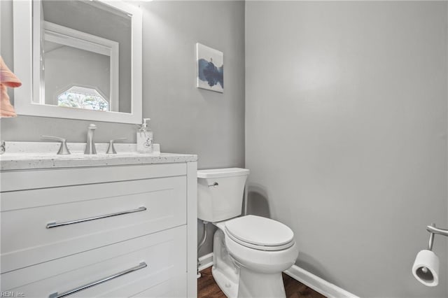 bathroom with hardwood / wood-style flooring, vanity, and toilet