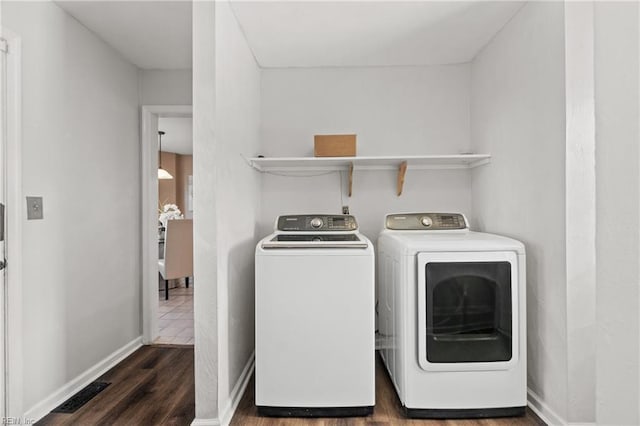 washroom with washer and clothes dryer and dark wood-type flooring