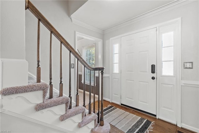 foyer entrance with ornamental molding and dark wood-type flooring