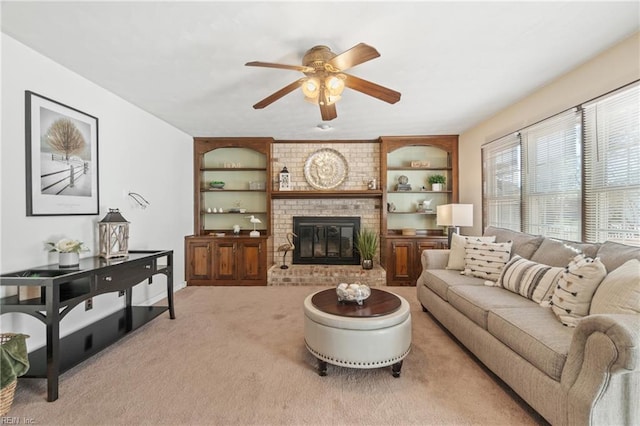 carpeted living room featuring built in shelves, ceiling fan, and a fireplace