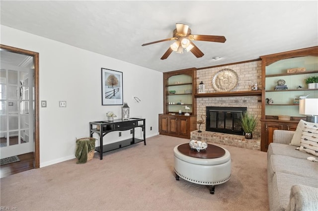 living room with carpet, ceiling fan, a fireplace, and built in shelves