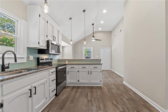 kitchen with kitchen peninsula, stainless steel appliances, vaulted ceiling, decorative light fixtures, and white cabinets