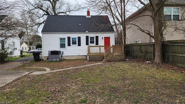 rear view of property featuring central AC unit, a shingled roof, a chimney, and fence