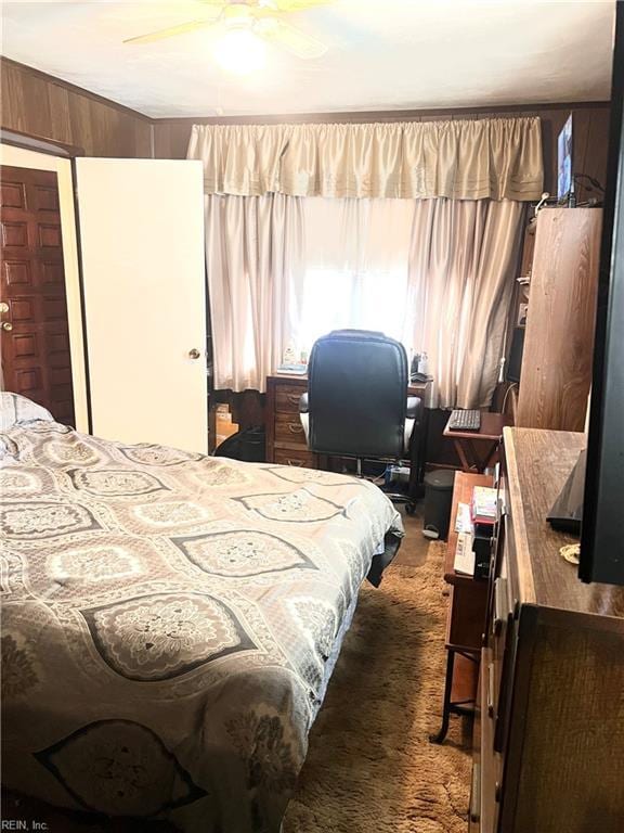 bedroom featuring dark colored carpet, ceiling fan, and wooden walls