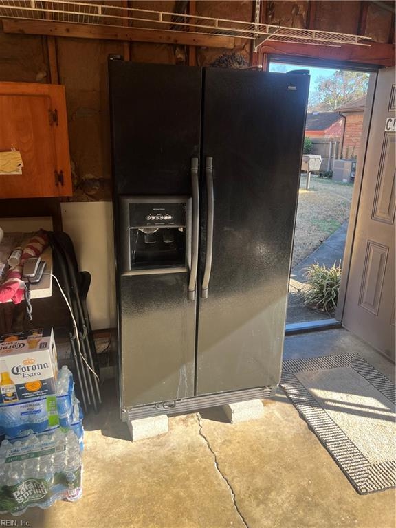 interior space with concrete flooring and black refrigerator with ice dispenser