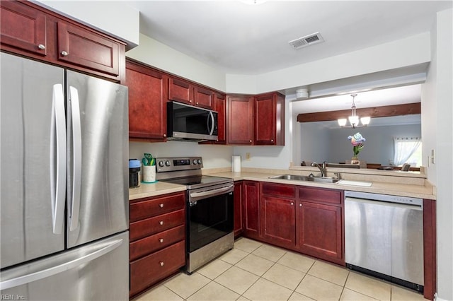 kitchen with an inviting chandelier, stainless steel appliances, sink, decorative light fixtures, and light tile patterned flooring