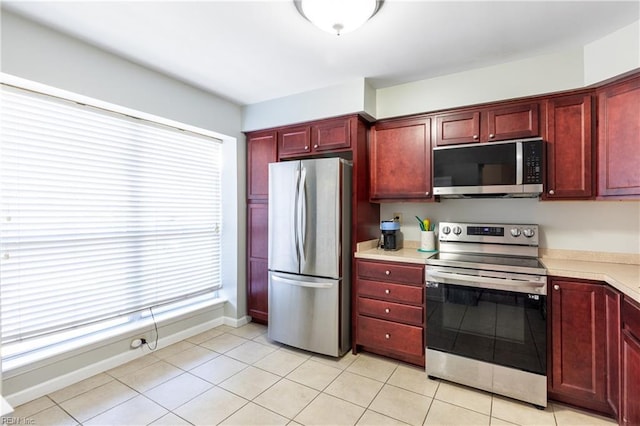 kitchen with appliances with stainless steel finishes, light tile patterned floors, and a healthy amount of sunlight