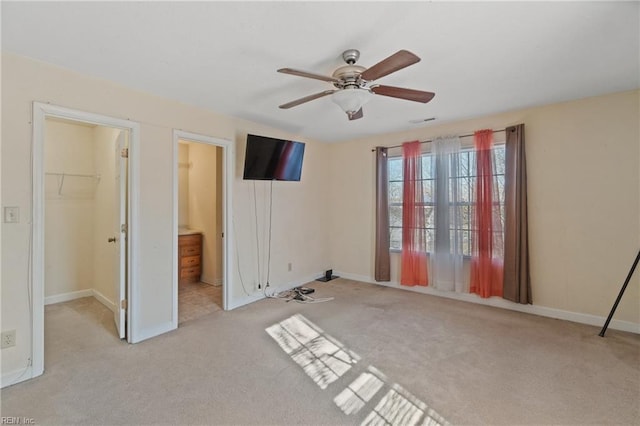 unfurnished bedroom featuring ceiling fan, light colored carpet, a walk in closet, and a closet