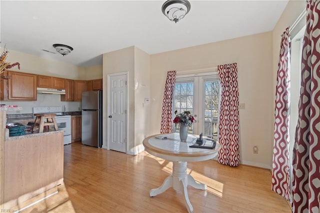 kitchen with stainless steel fridge, electric range, and light hardwood / wood-style flooring