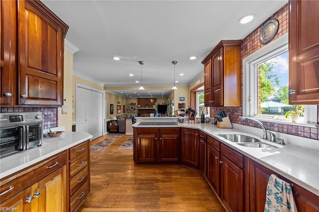 kitchen featuring sink, tasteful backsplash, dark hardwood / wood-style floors, crown molding, and decorative light fixtures