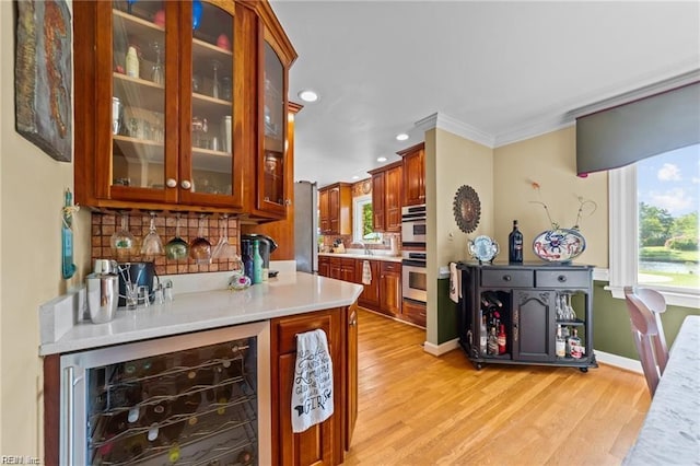 kitchen featuring decorative backsplash, wall oven, crown molding, light hardwood / wood-style flooring, and wine cooler