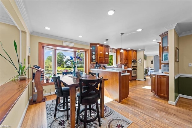 dining space with light wood-type flooring and ornamental molding