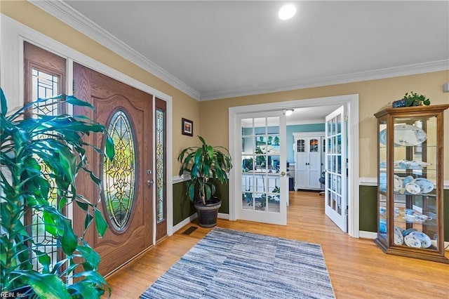 entryway featuring plenty of natural light, light wood-type flooring, ornamental molding, and french doors