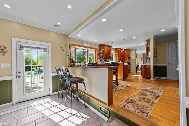 kitchen with kitchen peninsula, light wood-type flooring, ornamental molding, oven, and a breakfast bar area