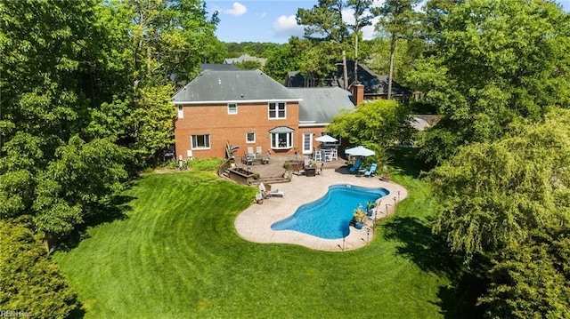 rear view of house featuring a lawn, a pool side deck, and a patio