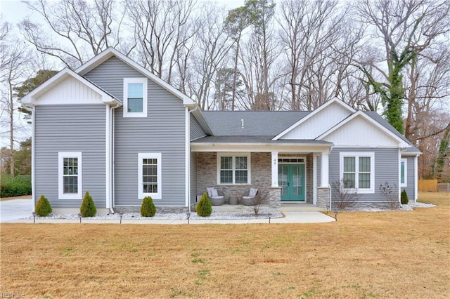 view of front of property featuring french doors, covered porch, and a front yard