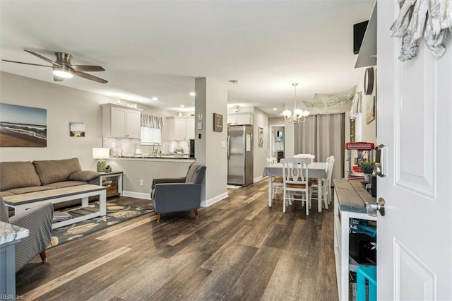 living room with dark hardwood / wood-style flooring, ceiling fan with notable chandelier, and sink