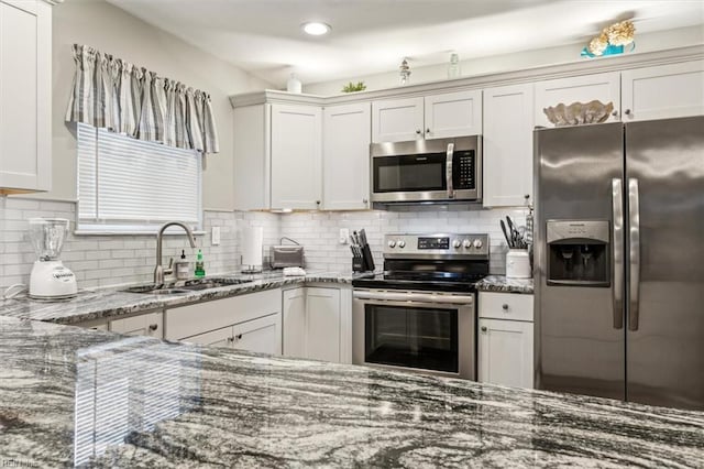 kitchen with white cabinetry, backsplash, appliances with stainless steel finishes, and dark stone counters