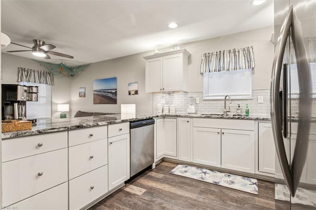 kitchen featuring white cabinets, appliances with stainless steel finishes, dark stone countertops, and sink