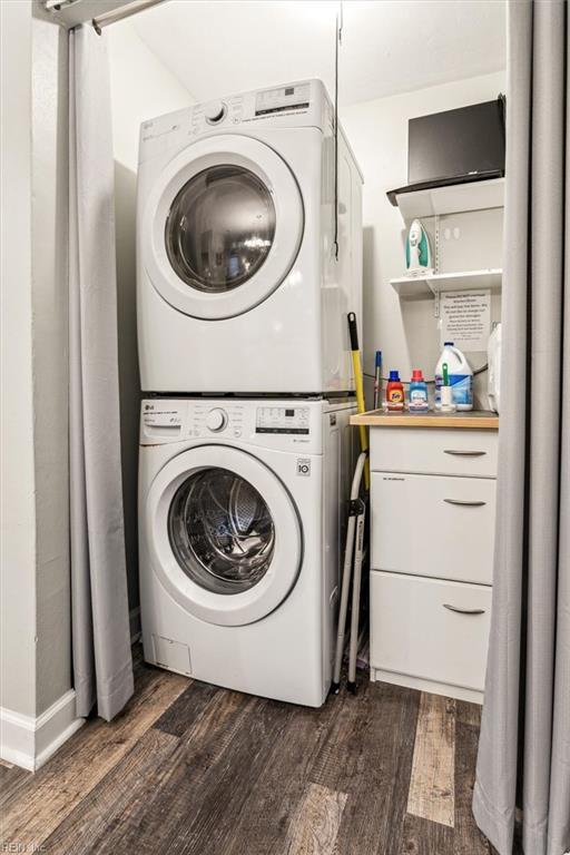 laundry room with dark hardwood / wood-style flooring and stacked washer and clothes dryer