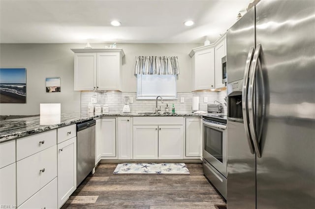 kitchen featuring appliances with stainless steel finishes, dark wood-type flooring, sink, stone counters, and white cabinets