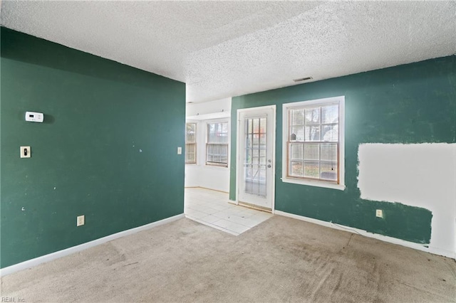 spare room with light colored carpet and a textured ceiling