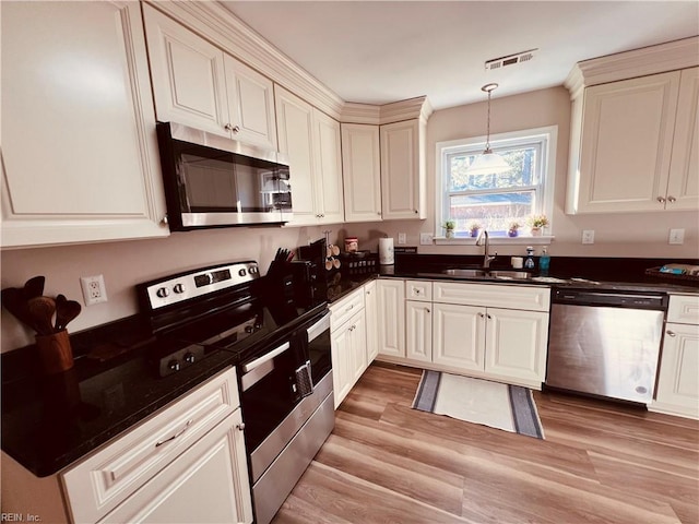 kitchen with decorative light fixtures, stainless steel appliances, light hardwood / wood-style flooring, and sink