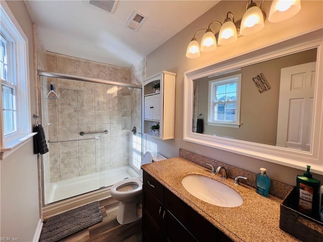 bathroom with hardwood / wood-style flooring, toilet, vanity, and walk in shower