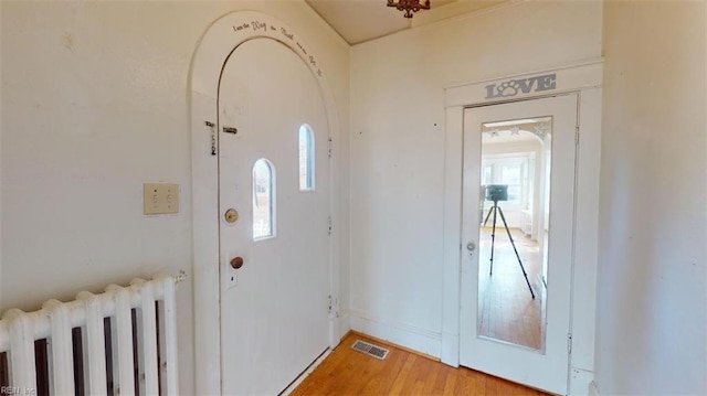 entryway with wood-type flooring and radiator heating unit