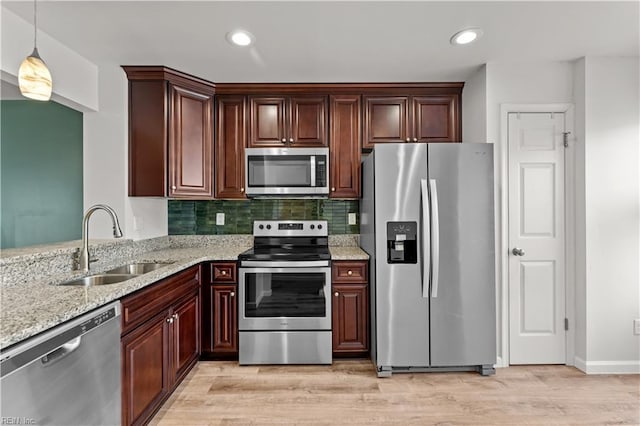 kitchen with sink, tasteful backsplash, decorative light fixtures, light hardwood / wood-style floors, and stainless steel appliances