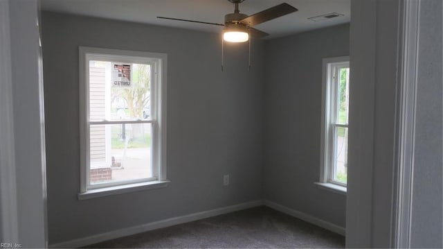 carpeted spare room featuring a wealth of natural light and ceiling fan