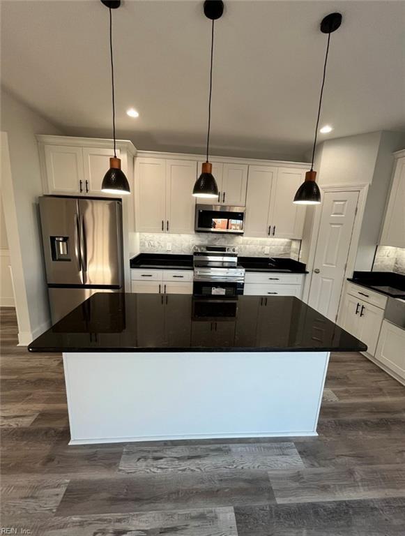 kitchen featuring white cabinets, stainless steel appliances, a kitchen island, and hanging light fixtures