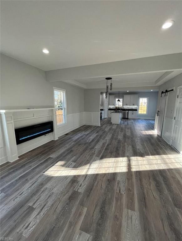 unfurnished living room featuring dark hardwood / wood-style flooring, a barn door, and a tray ceiling