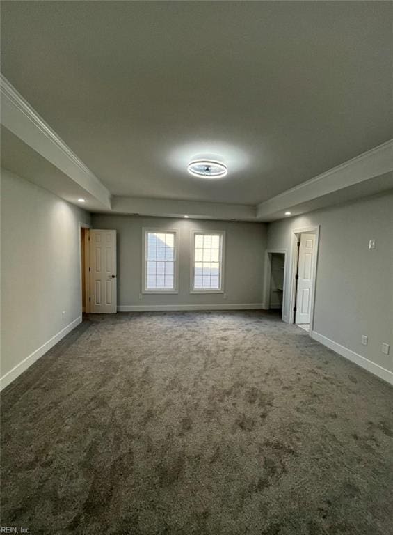 carpeted empty room with a raised ceiling and crown molding