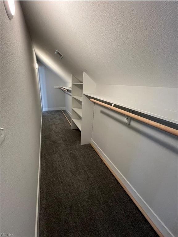 spacious closet with dark carpet and vaulted ceiling