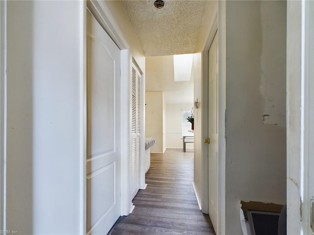 corridor with a textured ceiling and dark hardwood / wood-style floors