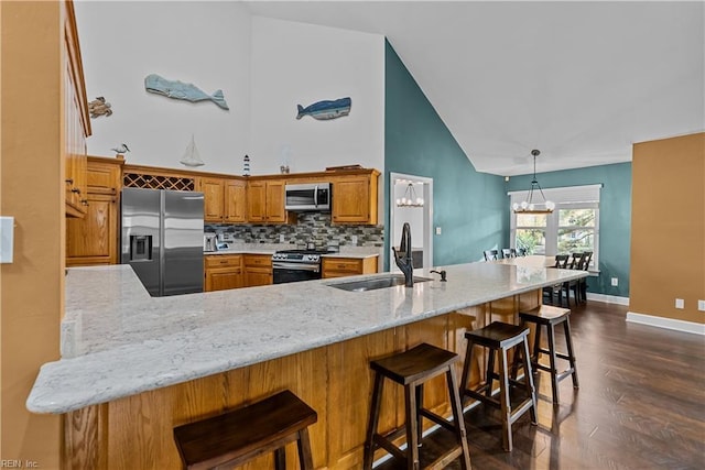 kitchen with decorative backsplash, appliances with stainless steel finishes, dark hardwood / wood-style flooring, kitchen peninsula, and sink