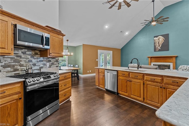 kitchen with decorative backsplash, ceiling fan with notable chandelier, stainless steel appliances, sink, and decorative light fixtures