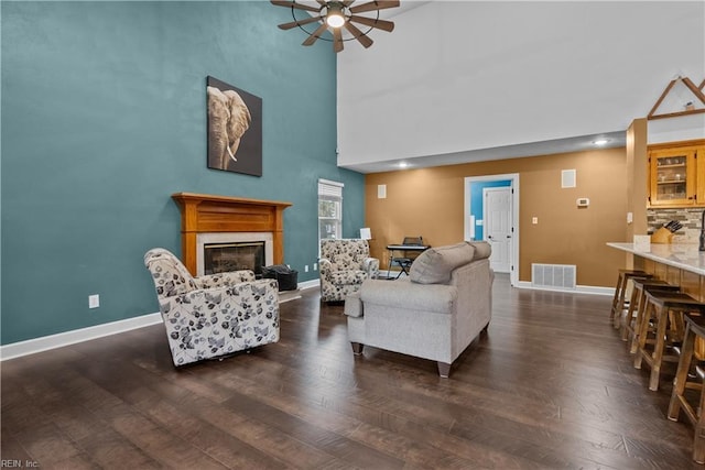 living room with dark hardwood / wood-style floors, ceiling fan, and a towering ceiling