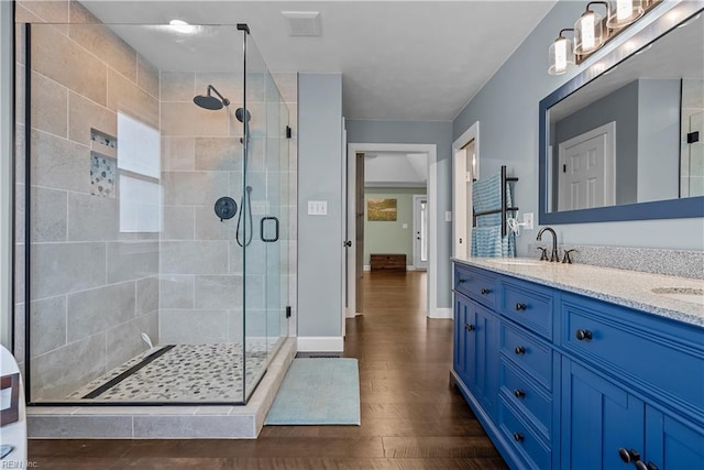 bathroom with hardwood / wood-style flooring, vanity, and walk in shower