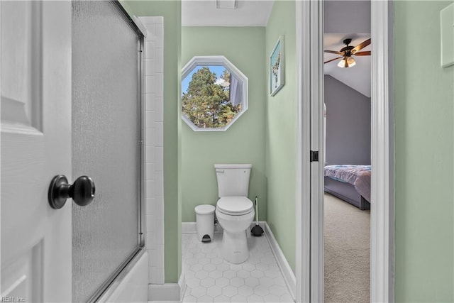 bathroom featuring toilet and bath / shower combo with glass door